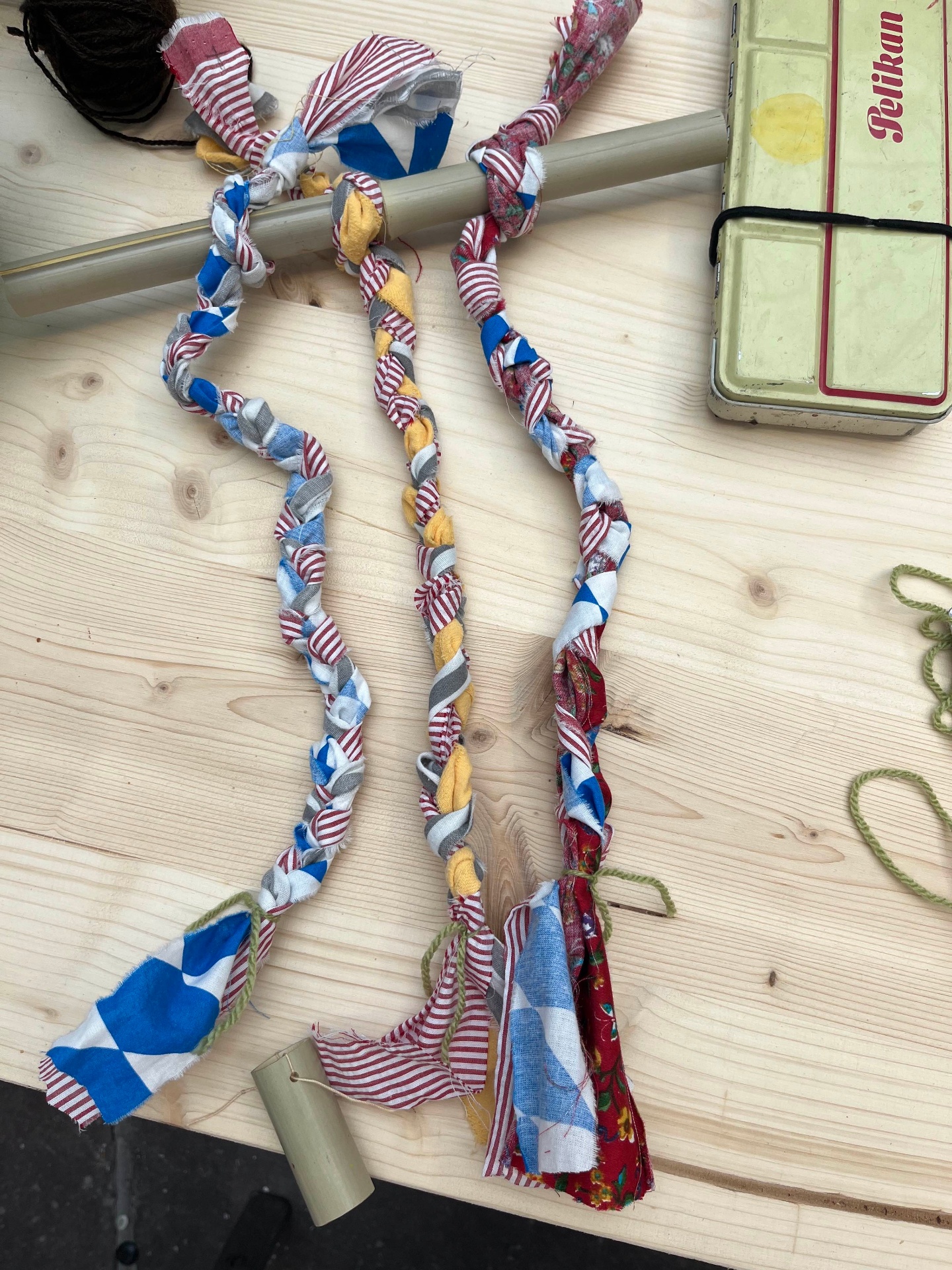 Finished braided fabric cords in red, blue, grey and yellow on the workshop table