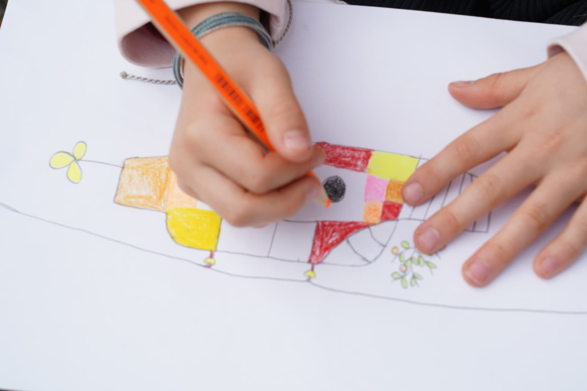 Child drawing a coloured submarine design with coloured pencils